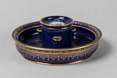 une assiette bleue et dorée sur laquelle figure une horloge