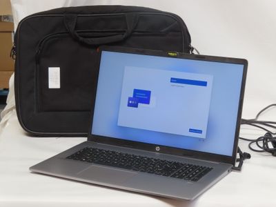 a laptop computer sitting next to a bag on a bed