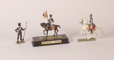 three figurines of soldiers on horses and a horse with a flag