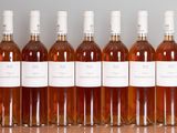 six bottles of wine are lined up on a wooden table