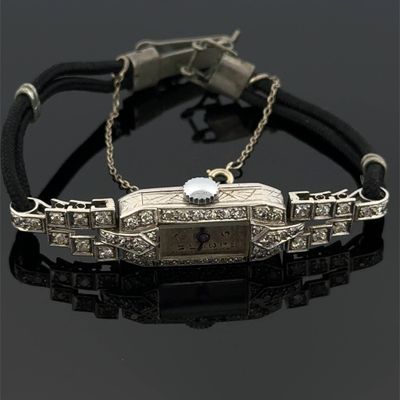 une image représentant un bracelet sur lequel est posée une montre, sur un fond noir