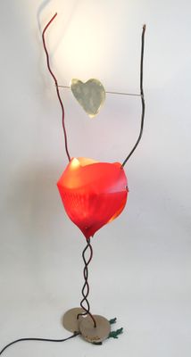 a red lamp that is on a stand on a white surface