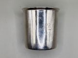 a silver cup that is sitting on a white surface
