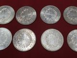 six silver coins are arranged in a row on a red surface