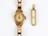 une image représentant une montre en or et un porte-clés posés sur une surface blanche