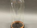 an image of a glass dome with a wooden base on a grey background