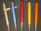 quatre stylos sont alignés en rang sur une surface noire