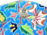 a picture of a decorative plate with flowers and a coat of arms on it