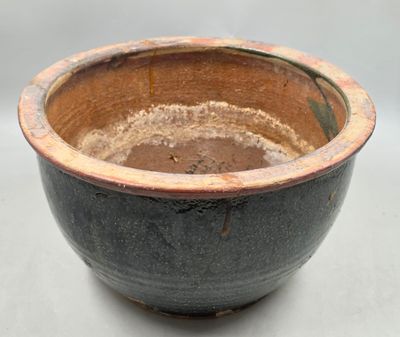 un bol marron et noir posé sur une surface blanche