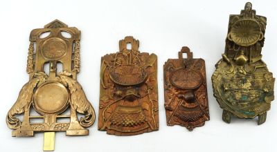 quatre heurtoirs de porte en laiton ancien sont alignés sur une surface blanche