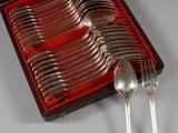 des couverts dans un coffret rouge posé sur une table où se trouvent d'autres couverts