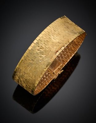 gros plan d'un bracelet en or sur une surface noire