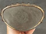 a person holding a silver plate with a design on it