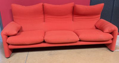 un canapé rouge orné de coussins, devant un mur rouge
