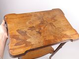 a person holding a small wooden table with a leaf design on it