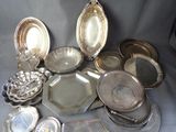 a lot of silver plates and trays sitting on a table