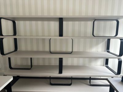 une étagère blanche sur laquelle sont posées des étagères noires, dans une pièce