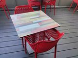 many red chairs and tables on the deck of a restaurant
