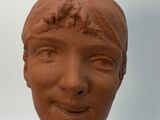 a clay sculpture of a woman ' s face on display