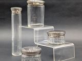 trois bocaux en verre transparent avec des couvercles argentés, posés sur une surface grise