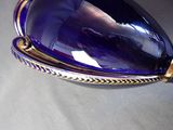 a purple glass pendant with a gold border around it