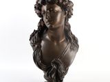 un buste en bronze représentant une femme avec des fleurs sur la tête