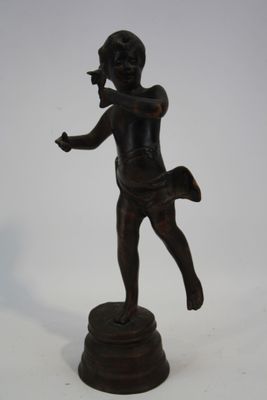 une statue en bronze représentant un garçon tenant une raquette de tennis