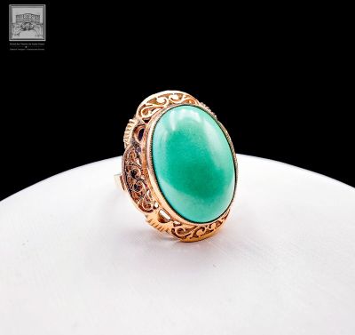 a gold ring with a green stone in the center