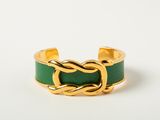 a close up of a gold ring with a green leather band