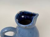 a small blue pitcher with a handle on a table