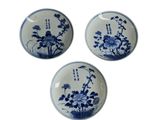 three blue and white plates with flowers on them on a white surface