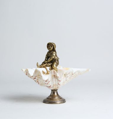 an antique bronze figurine of a woman sitting on a shell