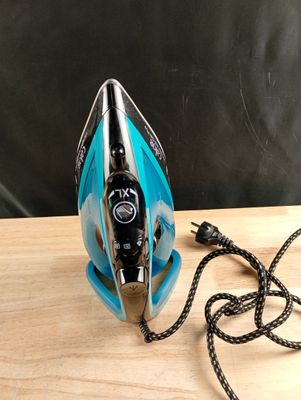 un fer à repasser bleu et noir posé sur une table en bois