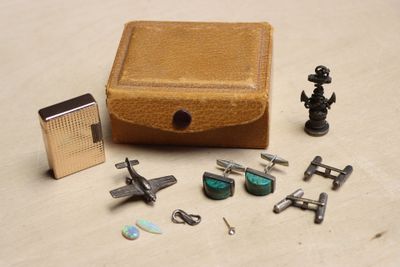 une petite boîte avec, à côté, une paire de boutons de manchette et un briquet
