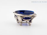 un bol en verre bleu posé sur un socle en argent