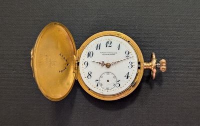 a gold pocket watch sitting on a black surface