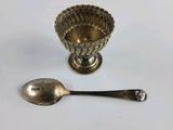 a silver spoon and a silver bowl on a white table