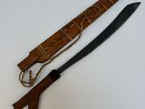 un vieux couteau en bois muni d'un manche en bois, posé sur une surface blanche