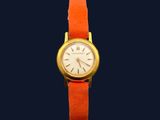 an image of a gold watch with a red strap on a blue background