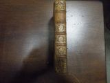 un vieux livre posé sur une table sur laquelle se trouve une horloge