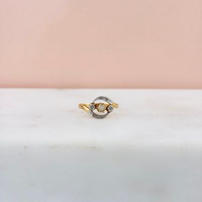 un gros plan d'une bague en or et diamants posée sur une surface en marbre