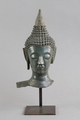 tête en bronze d'une statue de Bouddha posée sur un socle en bois