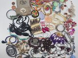 a pile of assorted necklaces and bracelets on a white surface