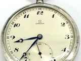 a close up of a silver pocket watch on a white surface