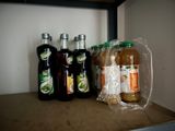 many bottles of liquid and a bag of food on a shelf