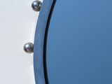 a round mirror on the side of a white wall