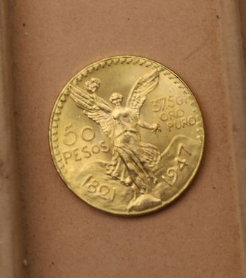 une pièce d'or sur laquelle est représenté un ange, posée sur une table