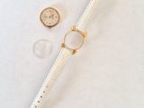 the watch is laying on a white surface next to a coin