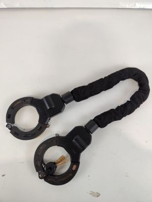une paire de menottes en métal noir posées sur une surface blanche