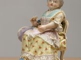 a figurine of a woman sitting on a chair